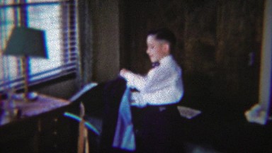 1954: Young boy dressing formal navy blue suit jacket bow tie.