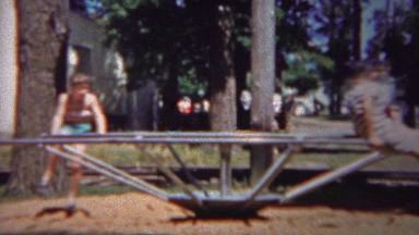 1954: Kids play spinning playground device learn circtrifical force.