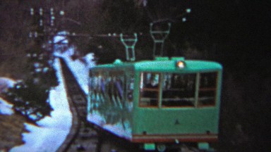 1956: Green passenger tram people moving train uphill winter snow.