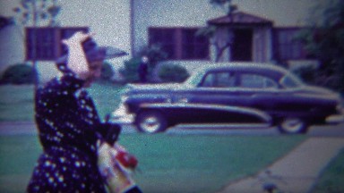 1954: Woman in Blue Polka Dot Dress Arriving at Event with Classic Car