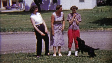 1959: Women Laughing and Playing with Black Dog Jumping