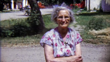 1959: Annoyed grandma roaming rural gravel driveway breaks smile.