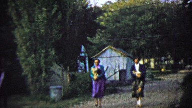 1959: Mother daughter walking back from local market down alley street.