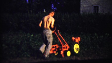 1959: Shirtless Man Mowing Thick Weeds on Rural Lawn with Industrial Machine