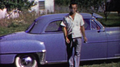 1958: Calm collected handsome man walking carefully from blue car.