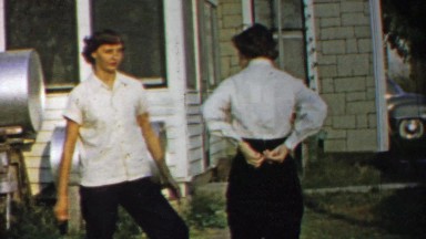 1958: Woman softball player swings arm simulating ball mit connection.