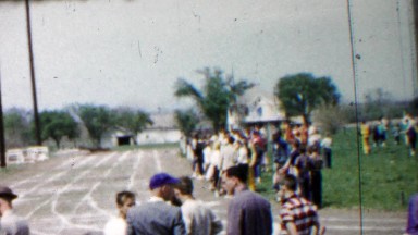 1958: High school track meet crowds wait for next event.