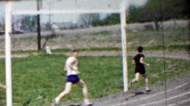 1958: Long distance high school track foot race rounding corner.