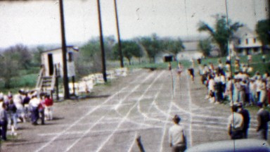 1958: High school track boys track running race turning corner.
