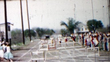 1958: High school boys track race hurdles event finishing line.