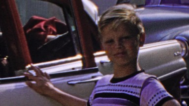 1964: Dad working in car while son admires classic beauty.