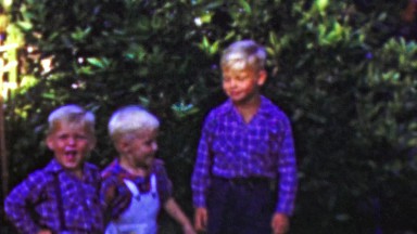 1964: Blonde brothers play outdoor summer blue colorful shirts.
