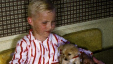 1964: Middle school boy plays new puppy hugs kiss cute small.