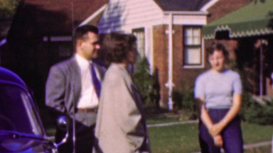 1964: Married couple meeting neighbors outdoor suburban home.