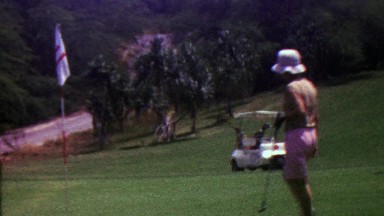 1963: Women removes golf green pin putting for birdie driving cart.