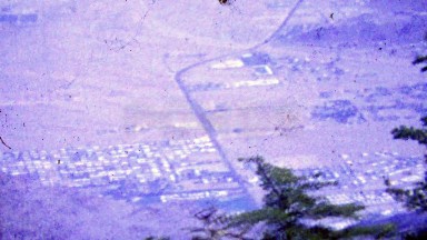 1964: City skyline grid below mountain overlook view.