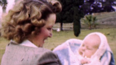 1957: Curly Haired Mother Enthralled with Newborn Baby in Park