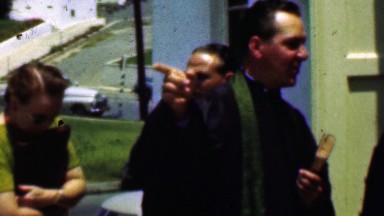 1957: Priest giving restaurant location advise outside community church.