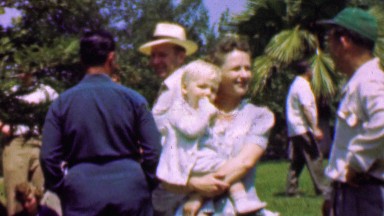 1957: Family outdoor park gathering mother holds blonde child.