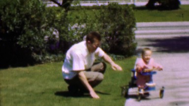 1957: Dad Helping Toddler Using Walking Training Device