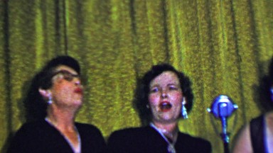 1957: Women trio singing old timey songs in matching shiny jewelry.