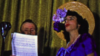1957: Singing couple dramatically performing sheet music song.
