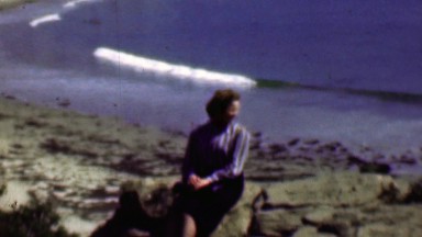 1958: Women resting beachside enjoying light ocean wave action.