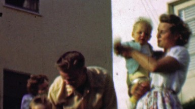 1957: Happy young family enjoying summer front porch sunshine.