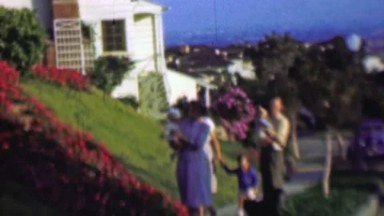 1957: Wealthy family walking home up hill flowers blooming.