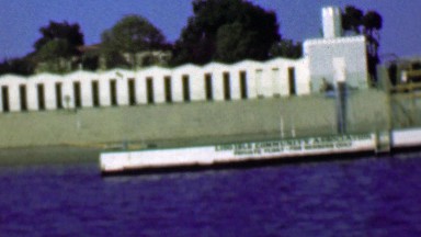 1958: Boat traveling upriver passing art deco style utilities building.