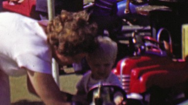 1961: Young blonde boy rides car carnival carousel amusement park.