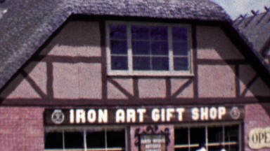 1962: Iron Art Gift Shop women shopper exits historic store.