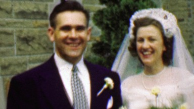 1961: Happy wedding couple excited outside stone classic church.
