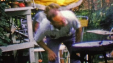 1957: Man Lighting Outdoor Bbq Grill by Blowing Air on the Fire.