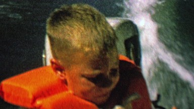 1962: Boy life jacket boat riding closeup smile.