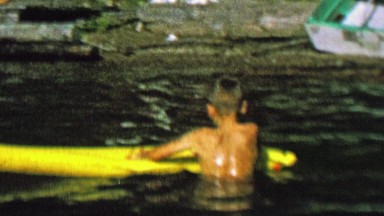 1962: Boy floating inflatable yellow raft water lake fun.