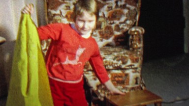 1967: Girl magician practice trick disappearing behind towel.