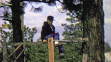 1962: Thug black hooded kid hanging monkey bars outdoor park.
