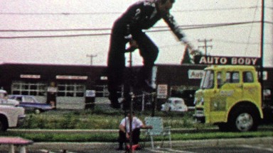 1967: Man rides tall unicycle pretends to have issues peddling.