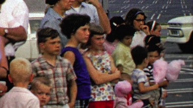 1967: Crowd of kids watch circus performance eating cotton candy.