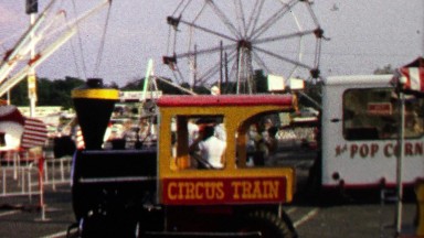 1967: Circus train carnival ferris wheel setup in mall parking lot.