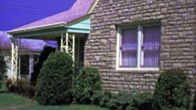 1964: Quaint brick facade bungalow suburban house garage driveway.