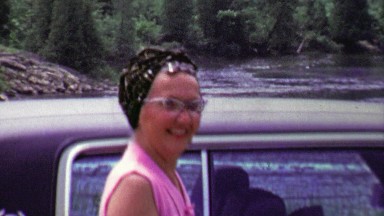 1961: Happy woman waiting by car after river fishing trip.