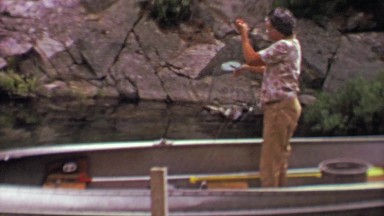 1961: Fisherman pulls up live fish stringer wire mesh basket.