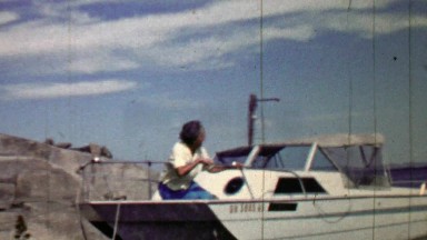 1957: Women awaits leisure boating sitting on boat front.