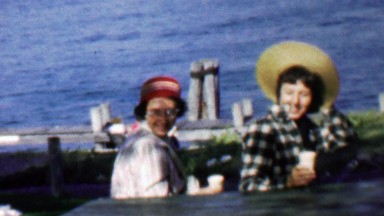 1957: Women enjoy waterfront coffee big wacky hats.