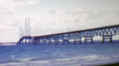 1957: Modern steel bridge over shallow blue water beach.