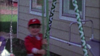 1967: Philadelphia Phillies baseball cap kid swing set having a blast.