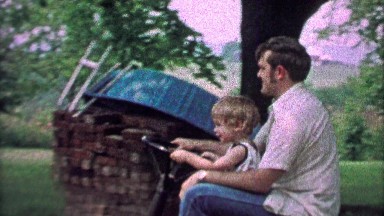 1967: Father lets son drive riding lawn mower across rural country yard.