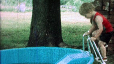 1968: Boy goes down kiddie slide into play swim pool with clothes on.